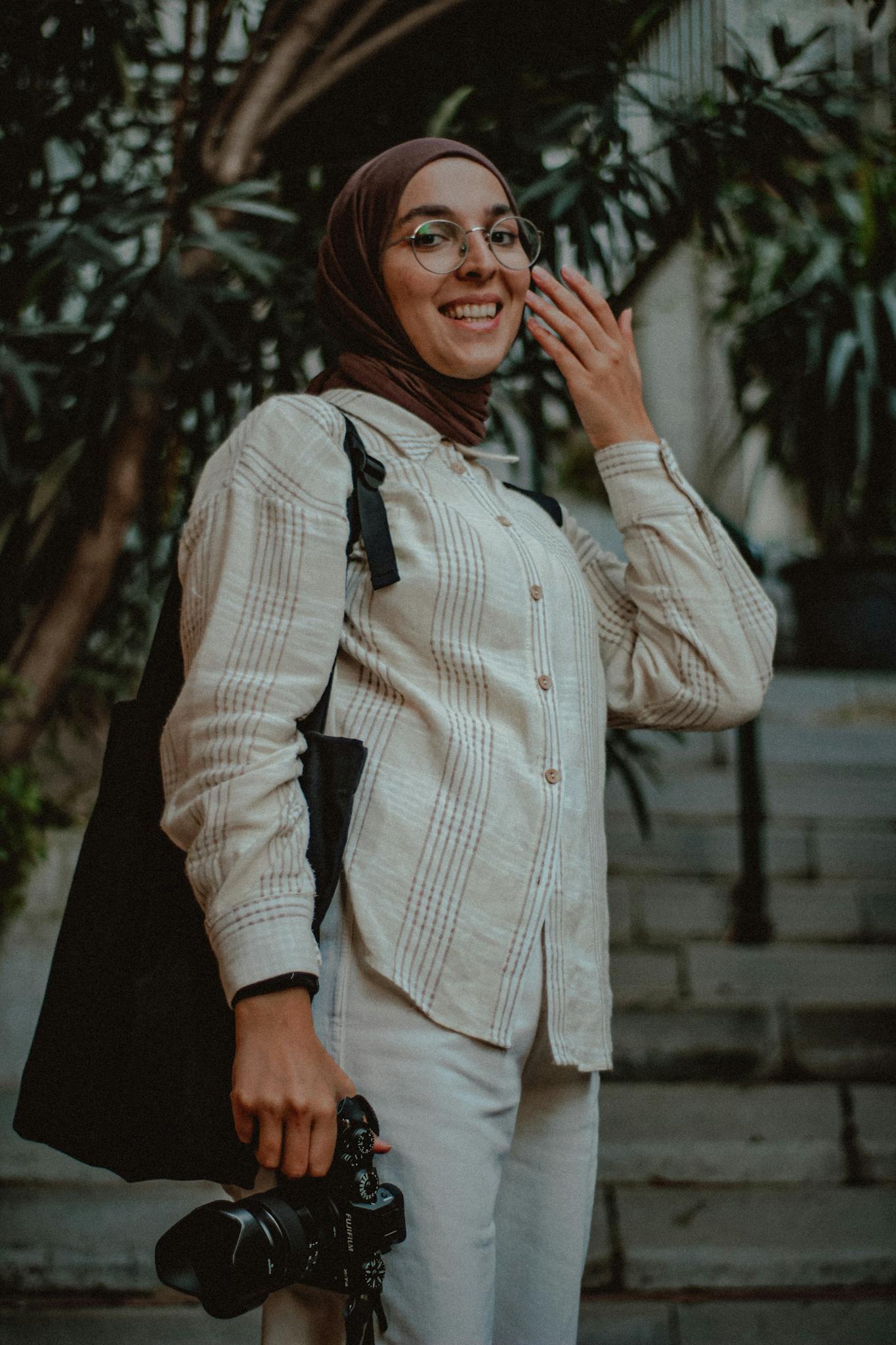 Smiling woman in hijab with DSLR camera, enjoying a day outdoors in Istanbul.